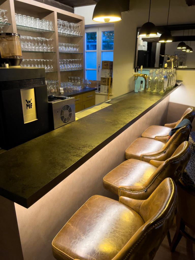 Bar beleuchtet mit Pendelleuchten in Cortenstahl-Optik und indirektem LED-Band - Restaurant Pala Hannover