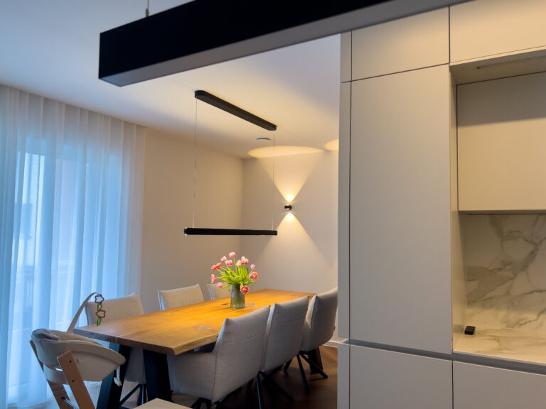 Essbereich mit moderner Pendelleuchte über dem Tisch und stilvollen Wandleuchten für indirekte Beleuchtung.