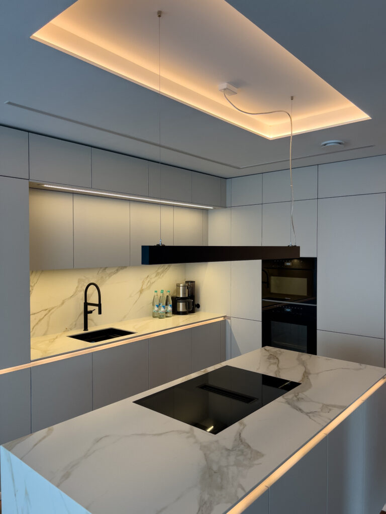 Moderne Küche mit indirekter LED-Beleuchtung in Decke, Schattenfuge und unter den Hängeschränken.