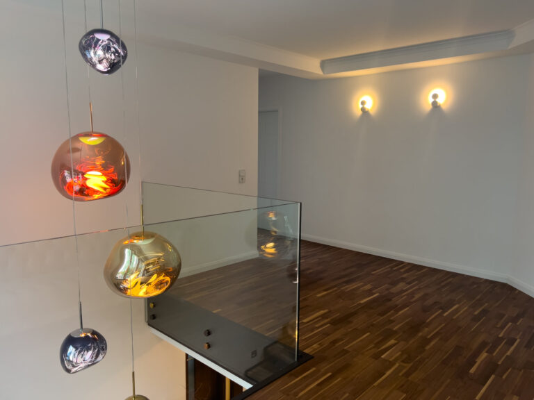 Treppenaufgang mit Designer-Pendelleuchten und stilvollen Wandleuchten
