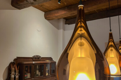Warme Glas-Pendelleuchte über Esstisch in rustikalem Bauernhaus mit Holzbalkendecke