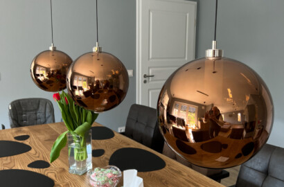 Esszimmer mit kupferfarbener Pendelleuchte über Holztisch