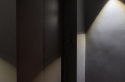 Dunkler Flur mit moderner Wandleuchte und indirekter Lichtfuge am Boden