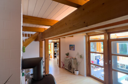 Indirekte LED-Deckenbeleuchtung zwischen Holzbalken im offenen Wohn- und Essbereich