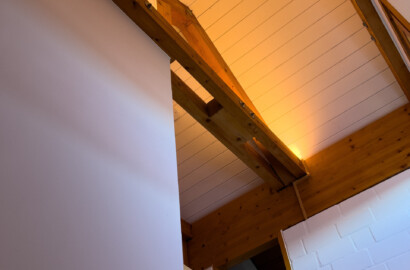 Indirekte LED-Beleuchtung an Holzbalken im Treppenaufgang mit warmer Lichtwirkung