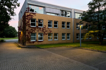 Außenbeleuchtung eines Bürogebäudes mit Wegebeleuchtung und Fassadenakzent bei Dämmerung