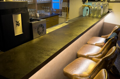 Barbereich mit Pendelleuchten, warmem Licht und beleuchteter Theke in stilvollem Gastronomieinterieur
