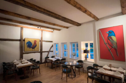 Restaurant mit Holzbalkendecke, warmem Lichtkonzept und akzentuierter Beleuchtung von Kunstwerken