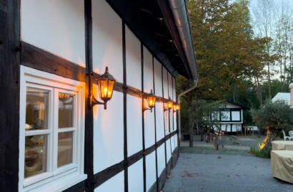 Fachwerkfassade mit klassischen Außenwandleuchten und warmem Licht entlang der Gebäudehülle
