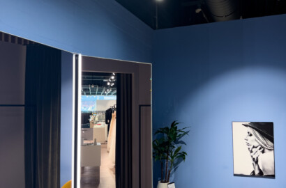 Vertikal beleuchteter Spiegel mit integrierten LED-Lichtlinien und runden Deckenleuchten im modernen Showroom