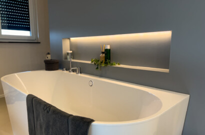 Indirekt beleuchtete LED-Wandnische über freistehender Badewanne im modernen Badezimmer