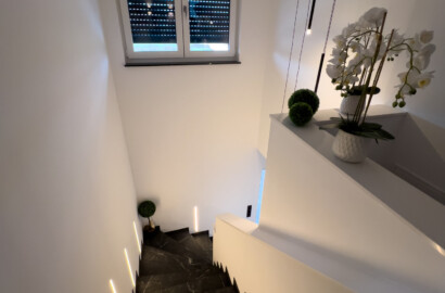 Integrierte LED-Stufenbeleuchtung mit warmem Licht in einem modernen, offenen Treppenhaus