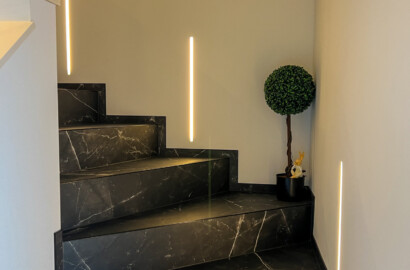 Vertikale LED-Lichtlinien zur sicheren und atmosphärischen Ausleuchtung einer modernen Treppe