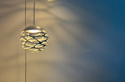 Filigrane Pendelleuchten mit warmem Licht und dekorativem Schattenspiel als atmosphärischer Lichtakzent an der Wand