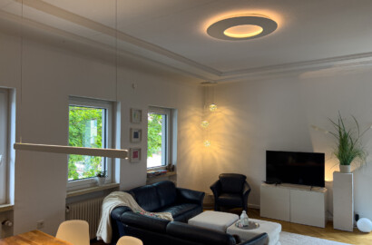 Lineare Pendelleuchte mit warmem, gleichmäßigem Licht über dem Wohnbereich in einem stilvollen Interieur