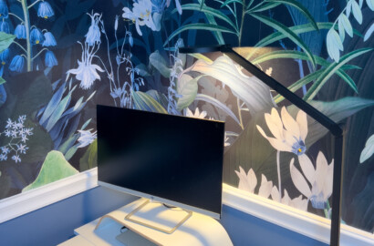 Moderne Schreibtischleuchte mit direkter und indirekter Lichtführung zur blendfreien Arbeitsplatzbeleuchtung vor botanischer Wandgestaltung