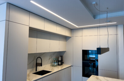 Lineare Pendelleuchte und integrierte LED-Lichtlinien zur klaren und wohnlichen Ausleuchtung einer modernen Küche
