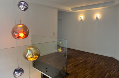 Treppenaufgang mit Designer-Pendelleuchten und stilvollen Wandleuchten