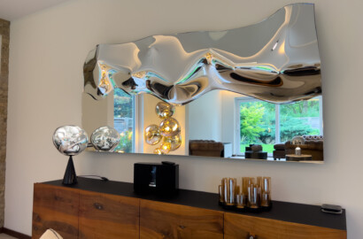 Designer-Spiegel reflektiert Stehleuchte und Lichtstimmung im modernen Wohnzimmer