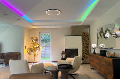 Wohnzimmer mit farbiger RGB-Deckenbeleuchtung und steuerbarem Smarthome-Lichtsystem