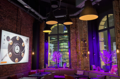 Lichtplanung in einem Restaurant mit Pendelleuchten, Akzentbeleuchtung und hervorgehobener Backsteinarchitektur.