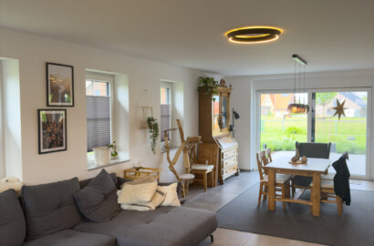 Offener Wohn- und Essbereich mit zwei warm leuchtenden LED-Ring-Deckenleuchten aus schwarzem Metall.